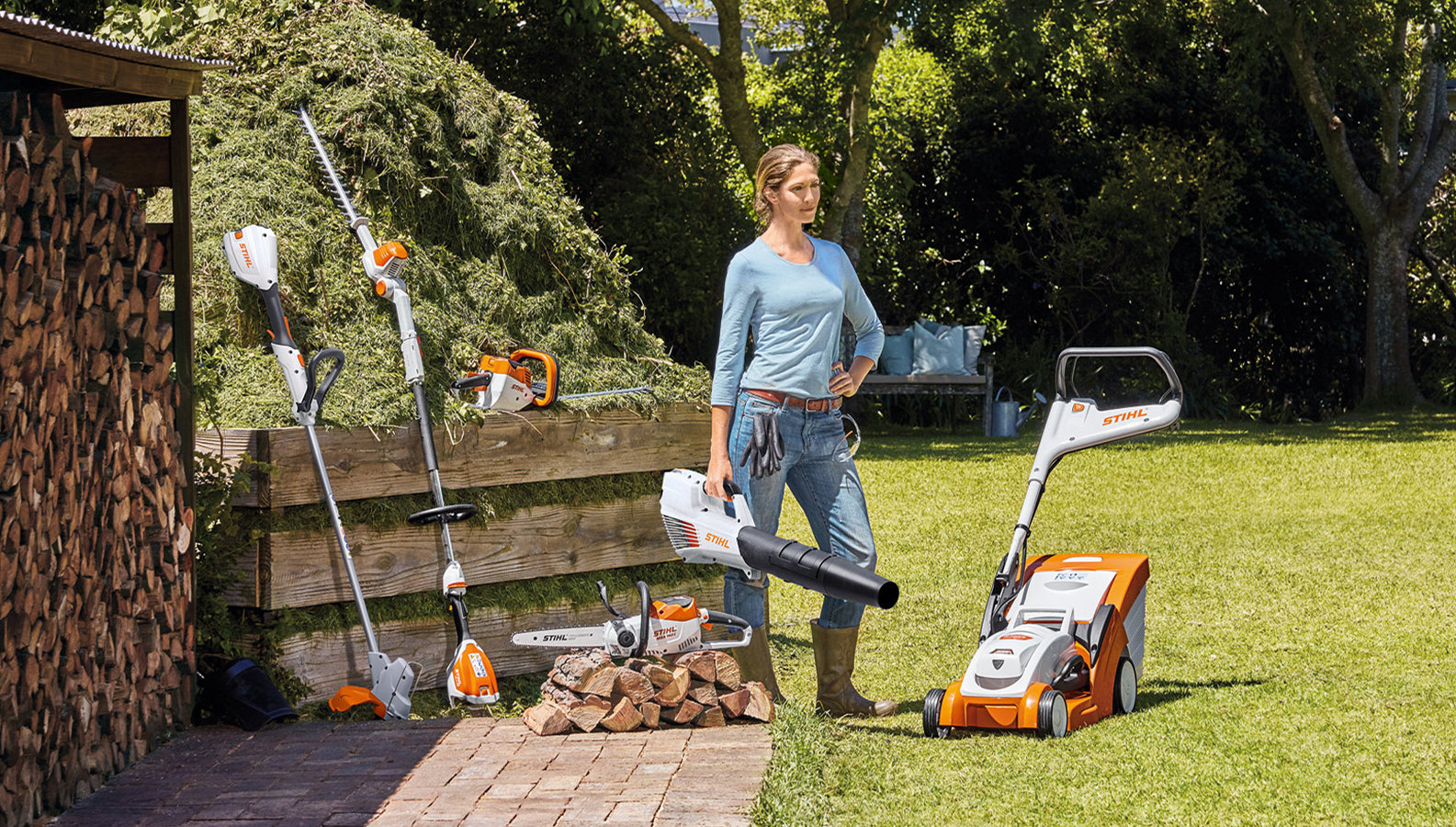 Mujer en el jardín con una selección de productos de batería STIHL