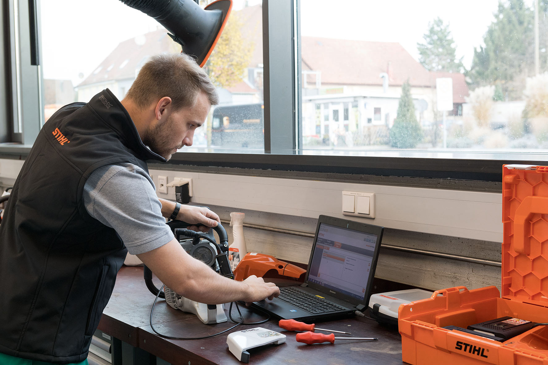 Soluciones digitales STIHL: un hombre mira la pantalla de un ordenador portátil con una motosierra STIHL al lado.