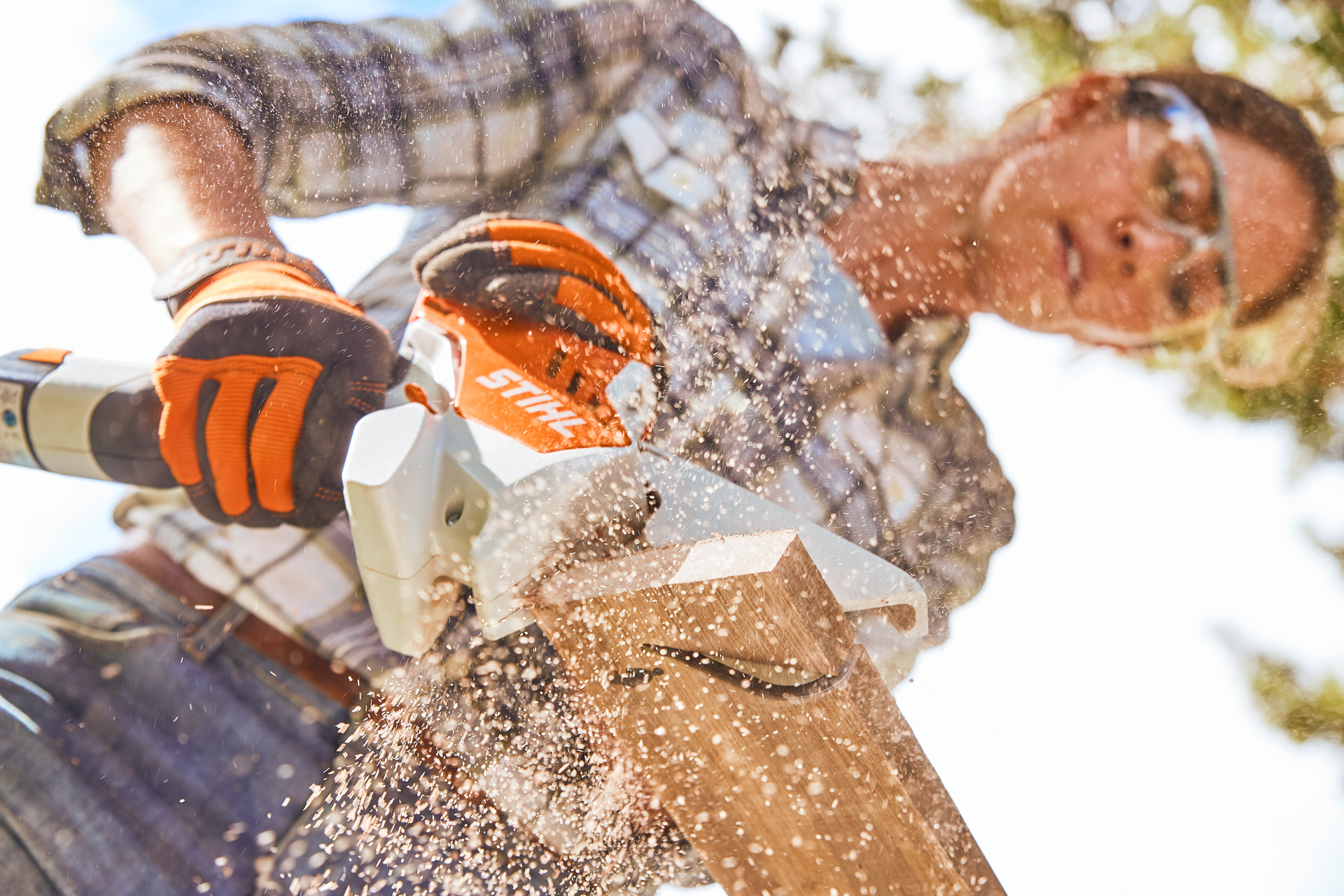 Una mujer con gafas de protección con la minisierra de batería de jardín STIHL GTA 26 