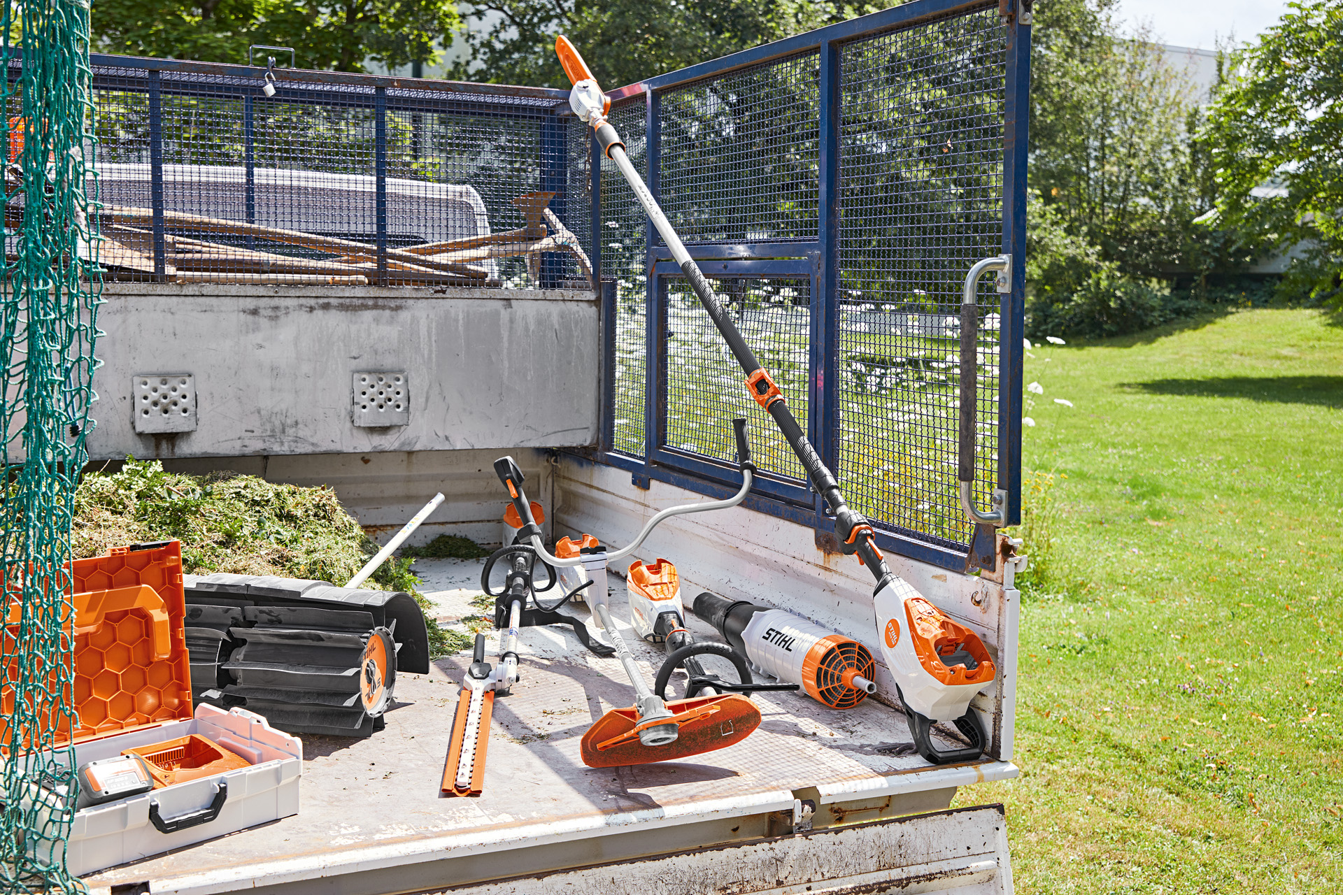 Vehículo con podadora de altura STIHL HTA 135, cortasetos de altura HLA 135, motoguadaña FSA 135 y KMA 135 en la superficie de carga