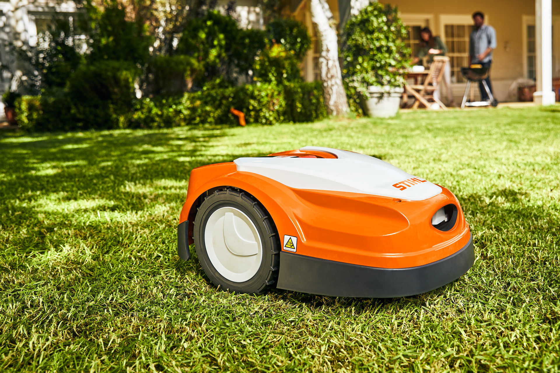 Un robot cortacésped STIHL iMOW® RMI 422 sobre el césped delante de una casa