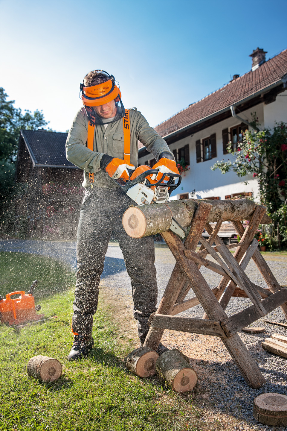 Un hombre con ropa de protección utilizando una motosierra de gasolina STIHL MS 170 para cortar el tronco de un árbol.