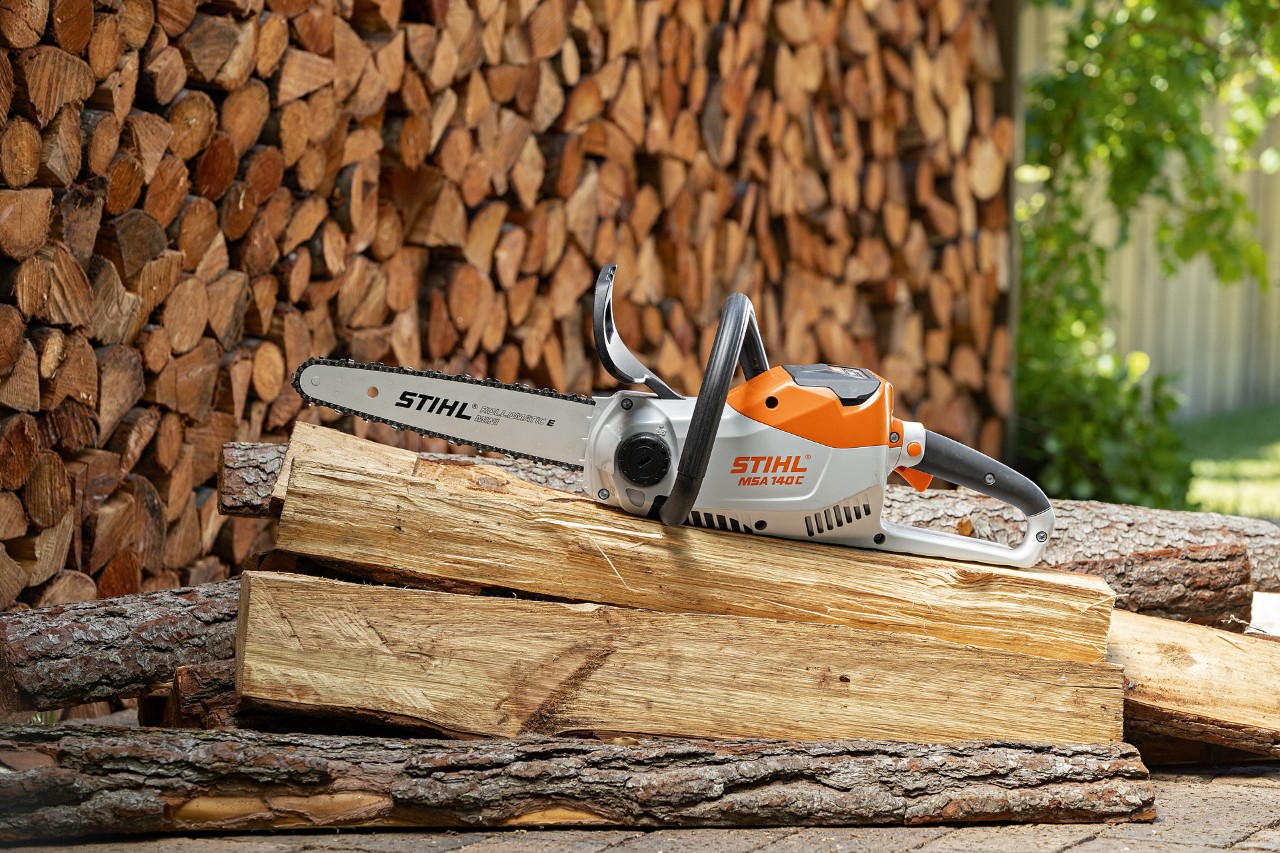 Motosierra de batería STIHL MSA 140 C-B sobre unos troncos largos preparados para hacer una casa de pájaros de madera.