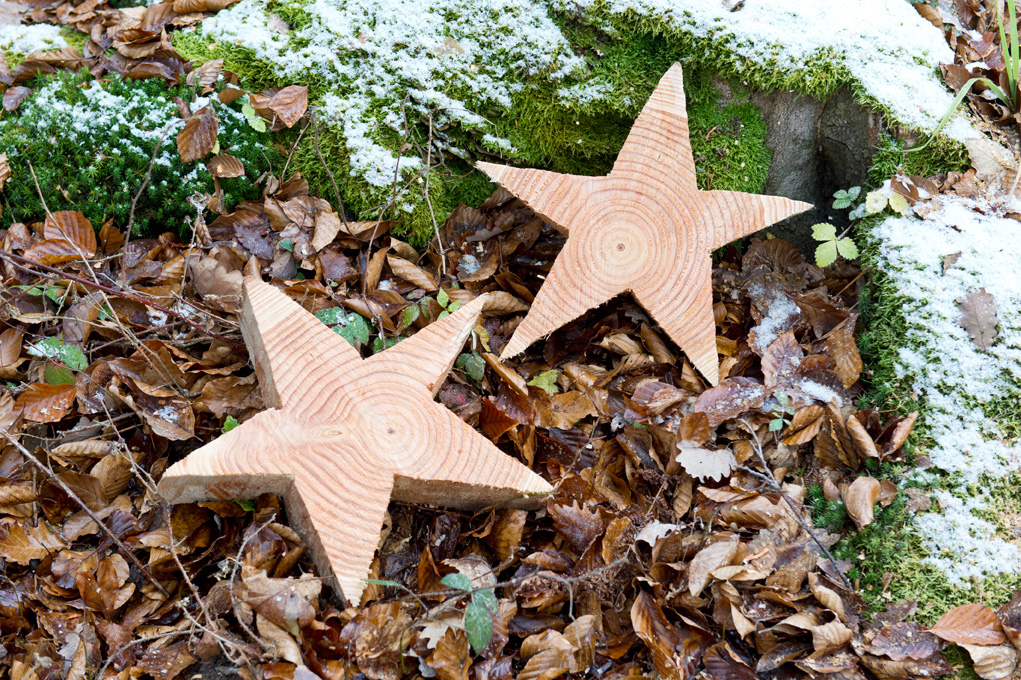 Haciendo una estrella de madera: dos estrellas de madera sobre hojas y musgo cubierto de nieve