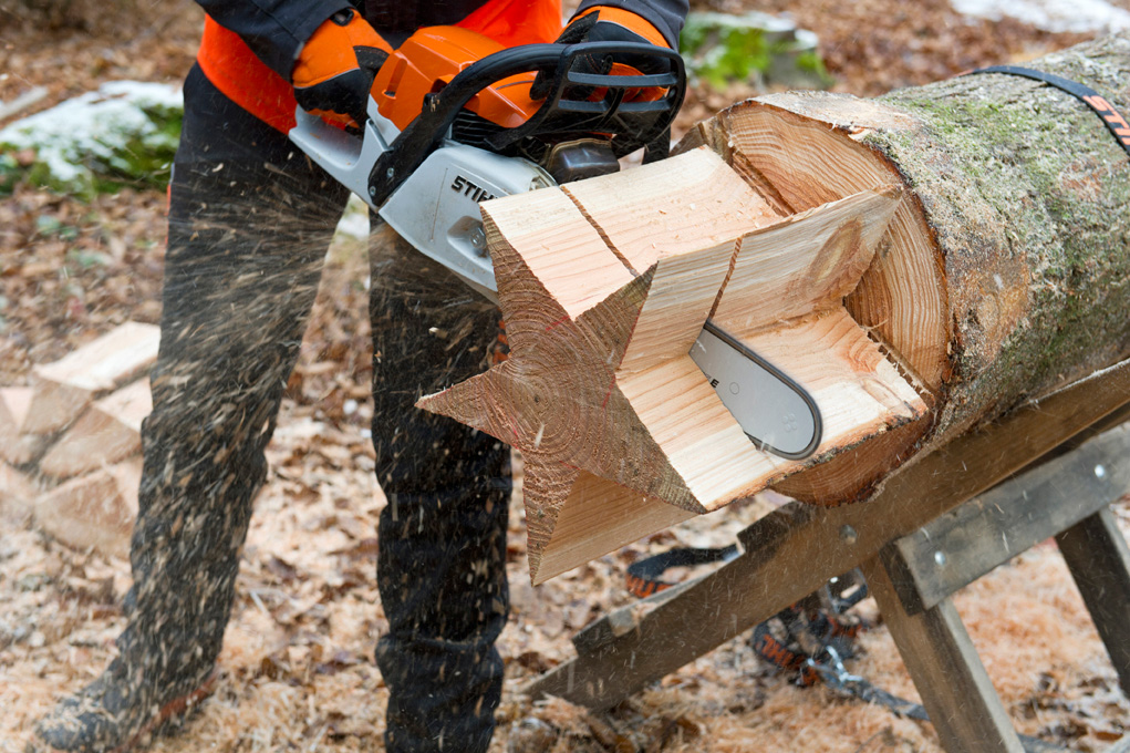 Haciendo una estrella: una persona corta un tronco con forma de estrella utilizando la motosierra STIHL MS 261 C-M