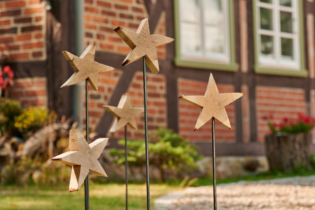 Cinco estrellas de madera con sus varillas colocadas en el suelo delante de una casa de ladrillo rojo