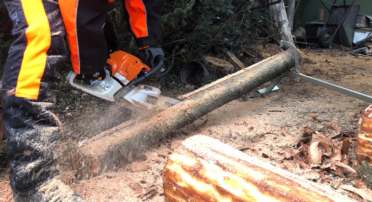 Un hombre con un equipo de protección STIHL cortando un tronco con una motosierra de gasolina STIHL MS 170.