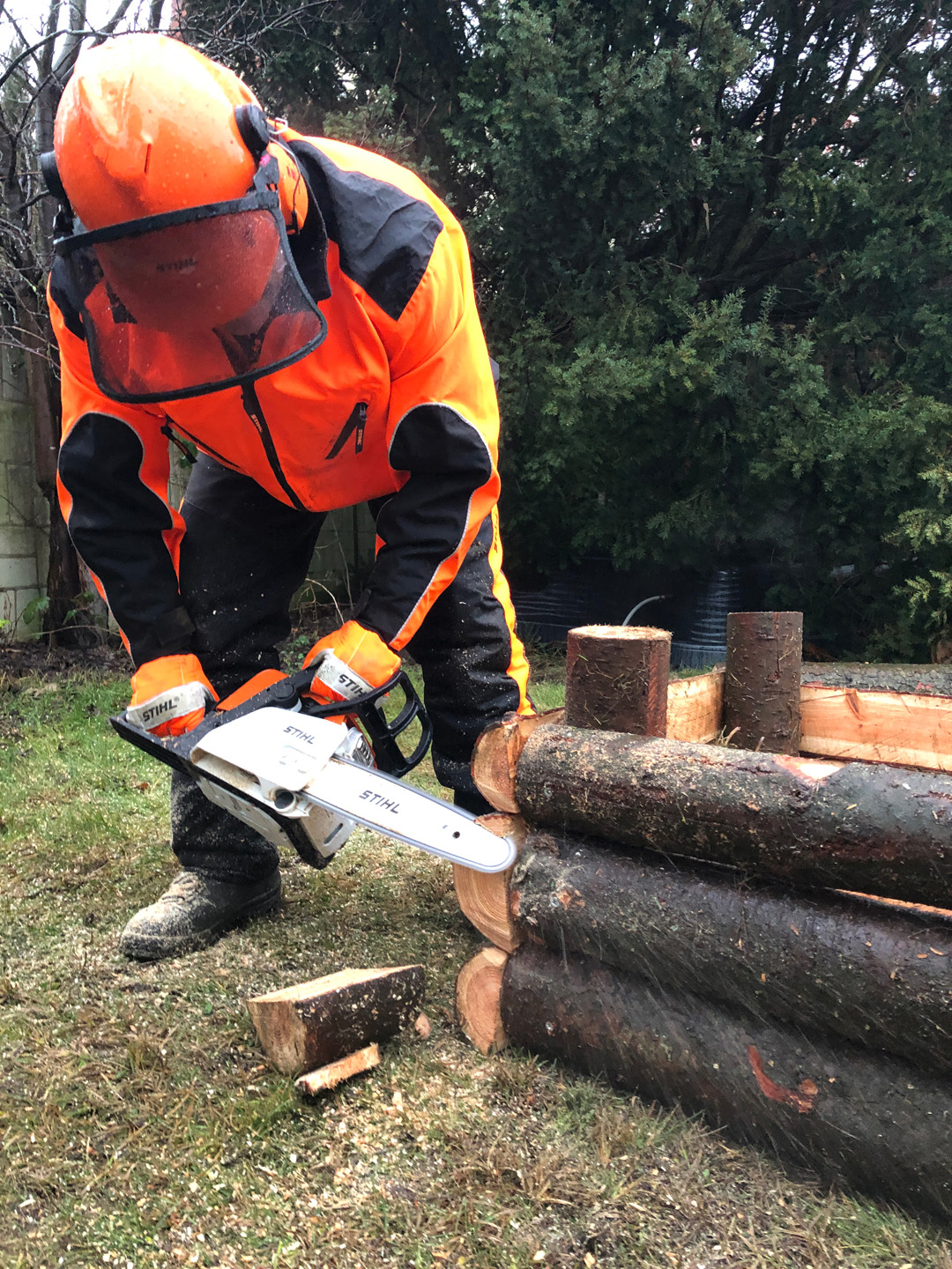  Un hombre con equipo de protección utiliza una motosierra STIHL MS 170 para recortar los troncos de una mesa de cultivo.