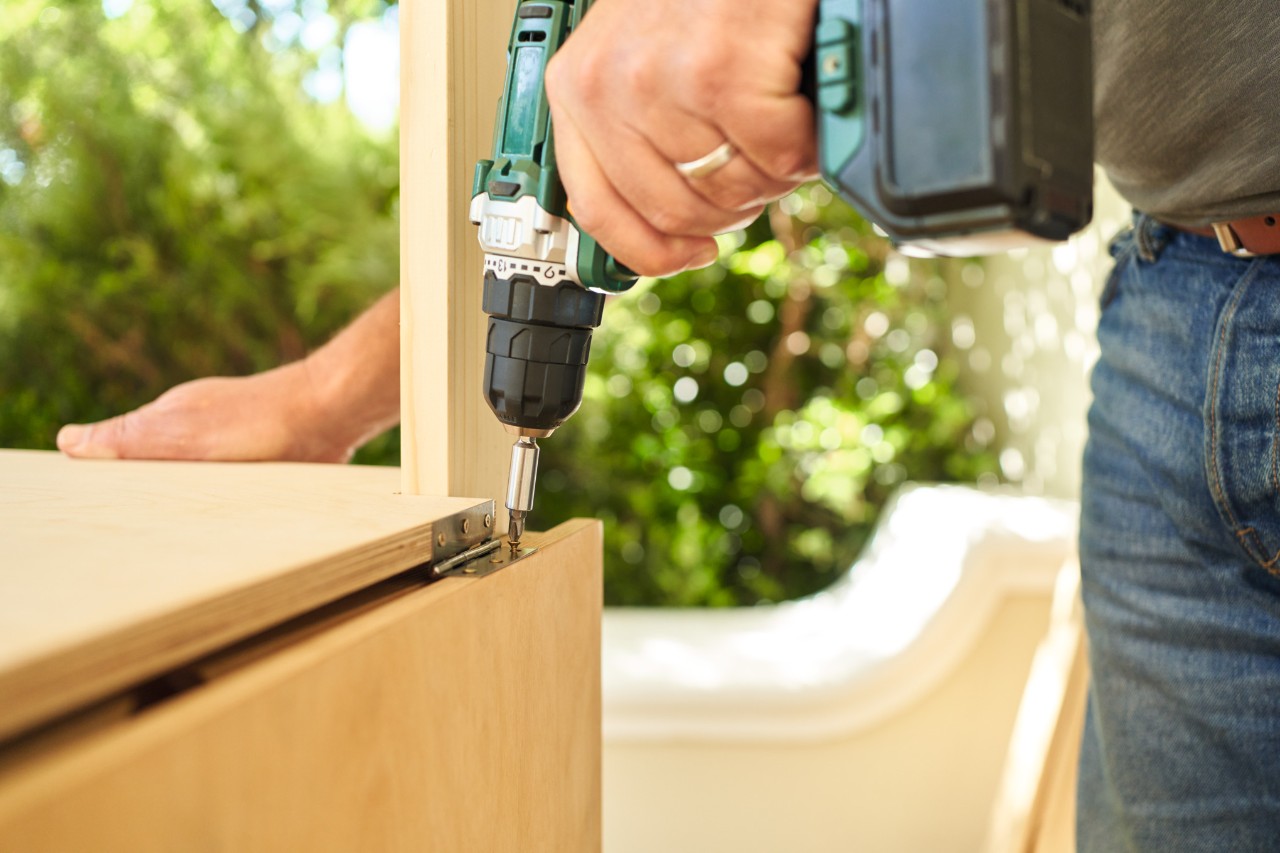 Primer plano de cómo se atornilla la placa adicional para una mesa de jardinería 