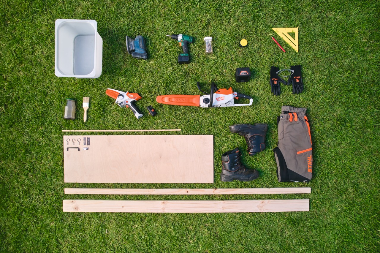 Materiales y herramientas para la construcción de un banco de trabajo de jardinería en una superficie de césped.