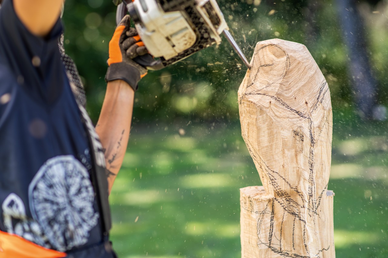 Una mujer añade detalles en la cara de un búho tallado en madera con una motosierra STIHL con equipo de corte específico para tallar.
