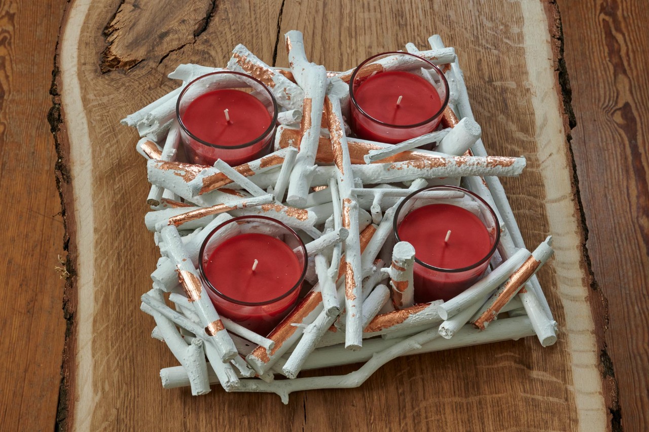 Crea tus coronas artesanales de Adviento: una corona de pequeñas ramas con cuatro velas rojas en portavelas 