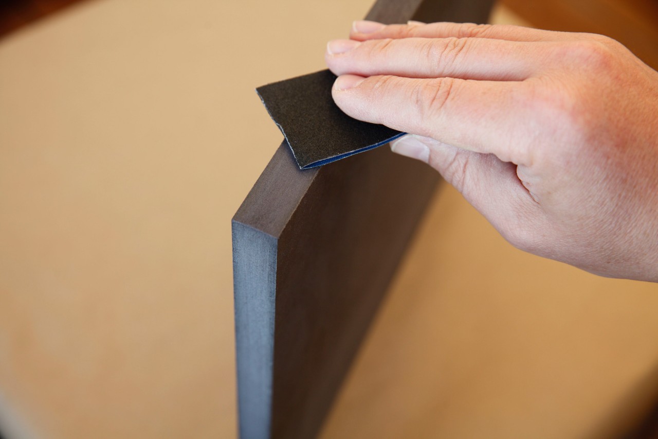 Taburete artesanal a partir de un tronco: primer plano del lijado de un borde cortado de un tablero de fibra de madera