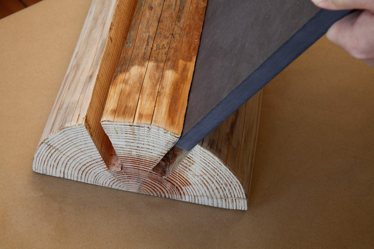 Taburete artesanal a partir de un tronco: inserción de un tablero de fibra de madera en una de las ranuras cortadas en un tronco partido