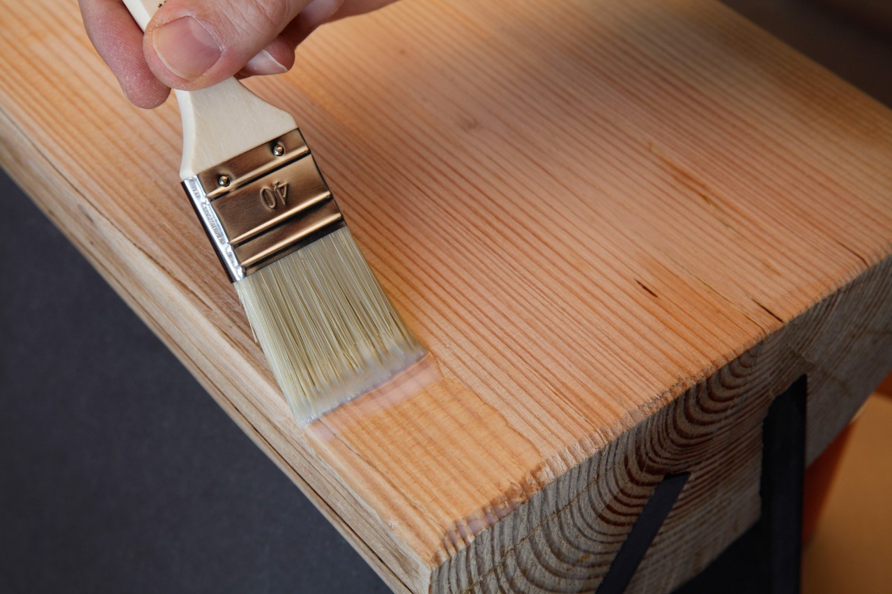 Taburete artesanal a partir de un tronco: Barniz de madera aplicado con una brocha sobre una superficie de madera preparada