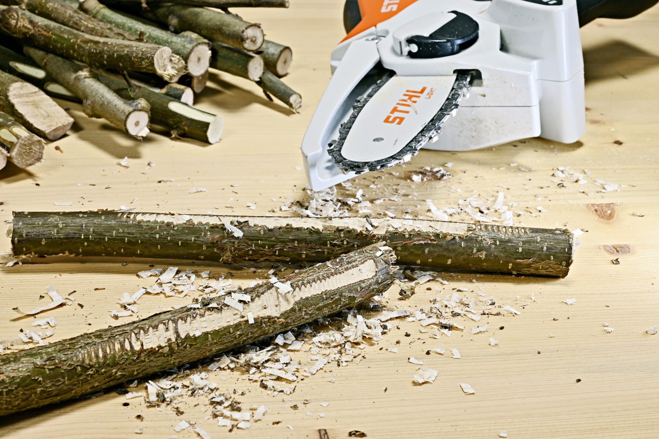 Decora con ramas: ramas con superficies rugosas y una minisierra de batería STIHL GTA 26 tras ellas