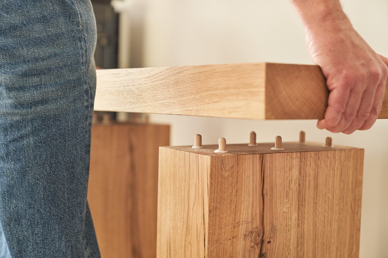 Una persona coloca una tabla de madera sobre vigas de madera con la ayuda de tacos 