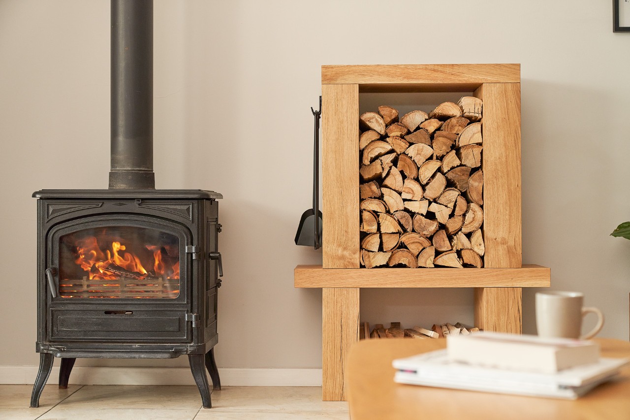 Chimenea y leñero interior lleno de troncos en una habitación 