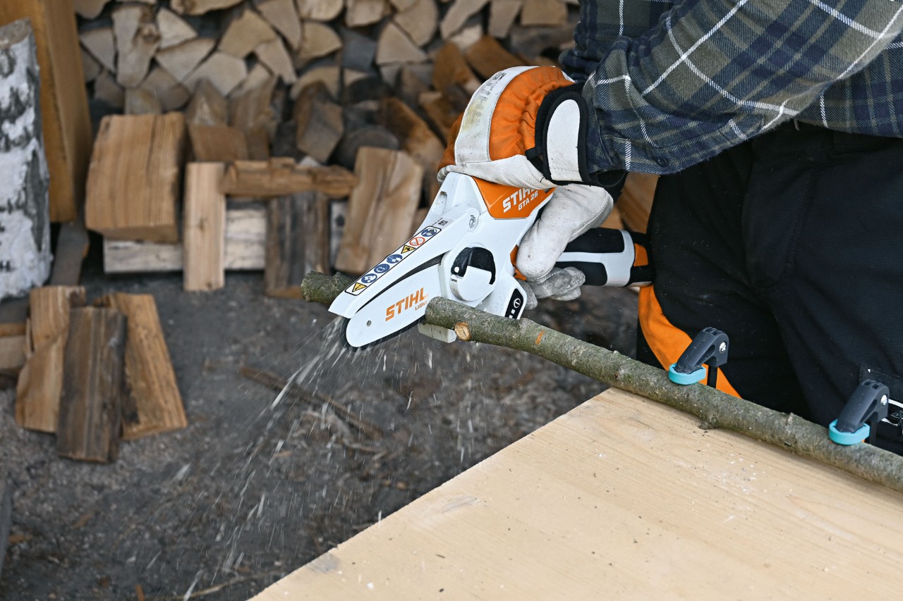 Primer plano de cómo una persona corta una rama con la minisierra de batería STIHL GTA 26