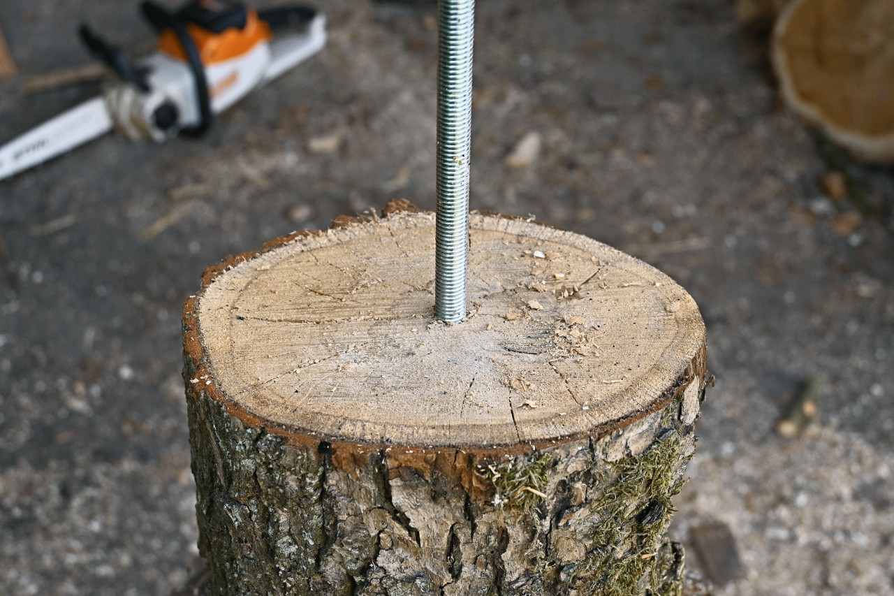 Primer plano de cómo taladrar una varilla roscada en un trozo de árbol