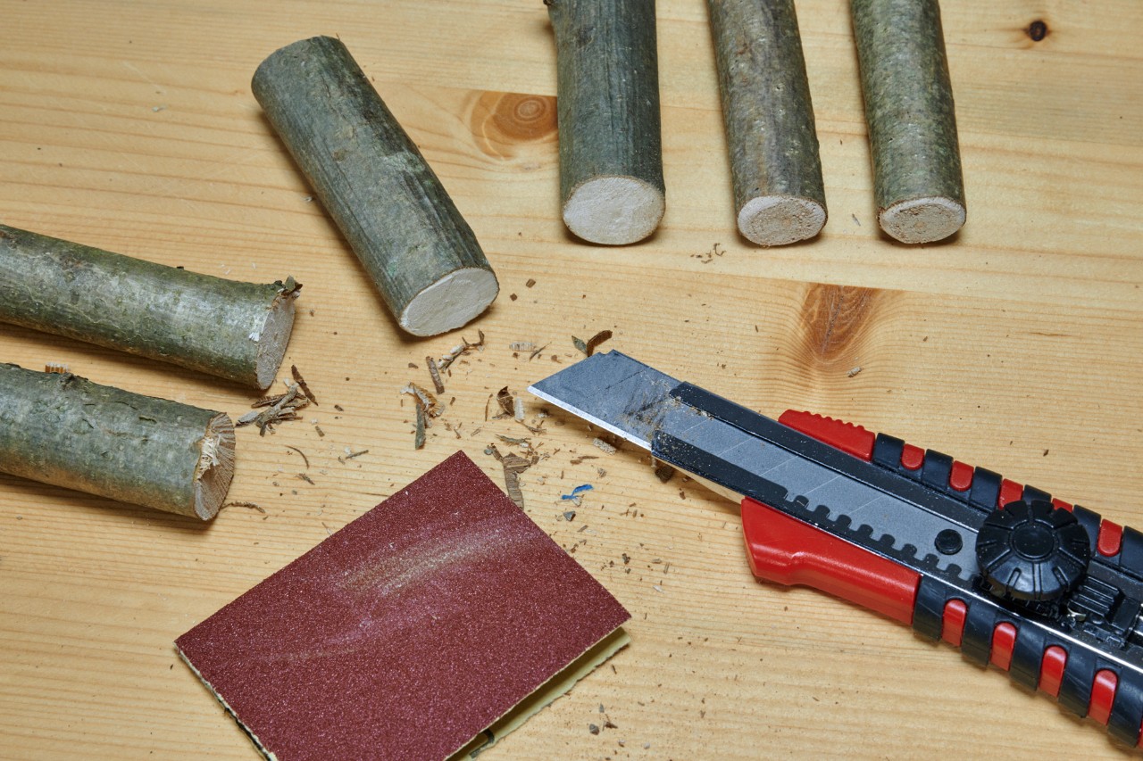 Crear un corazón con ramas secas: secciones de madera, papel de lija y un cuchillo multiusos.