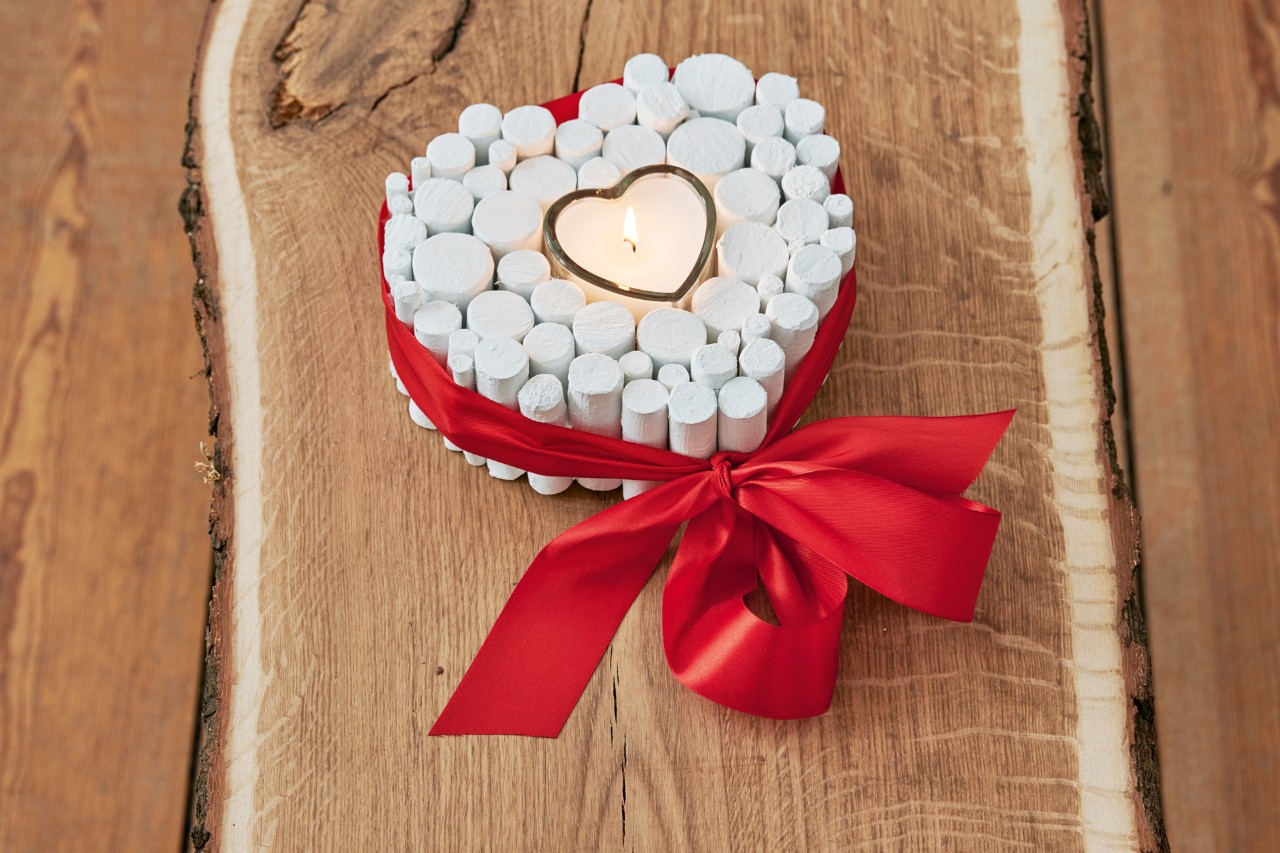 Crear un corazón de ramas: un adorno acabado con una vela encendida y un lazo rojo atado a su alrededor.