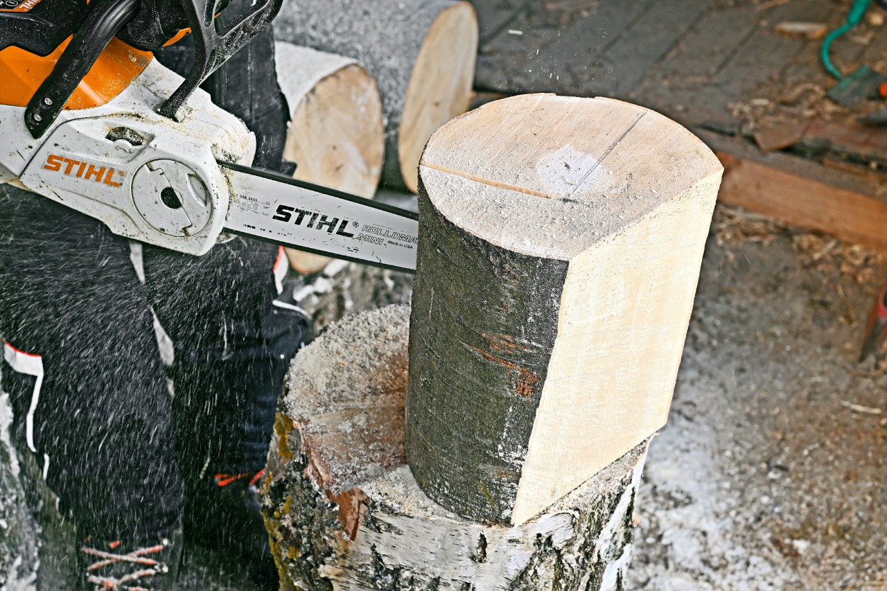 Una motosierra STIHL MSA 140 C cortando un tronco vertical.