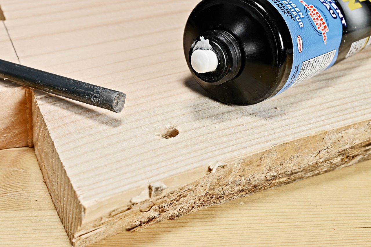 Haz tu mesa auxiliar DIY: adhesivo industrial y una barra de metal junto a un orificio perforado en la tabla de madera.