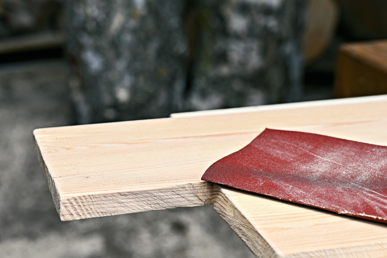 Papel de lija sobre una tabla de madera con un cuadrado recortado.
