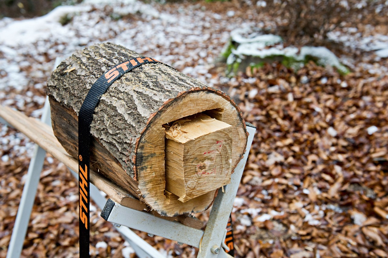 Lámpara artesanal de madera: tronco recortado con forma cuadrada y fijado a un caballete con una cinta tensora STIHL.