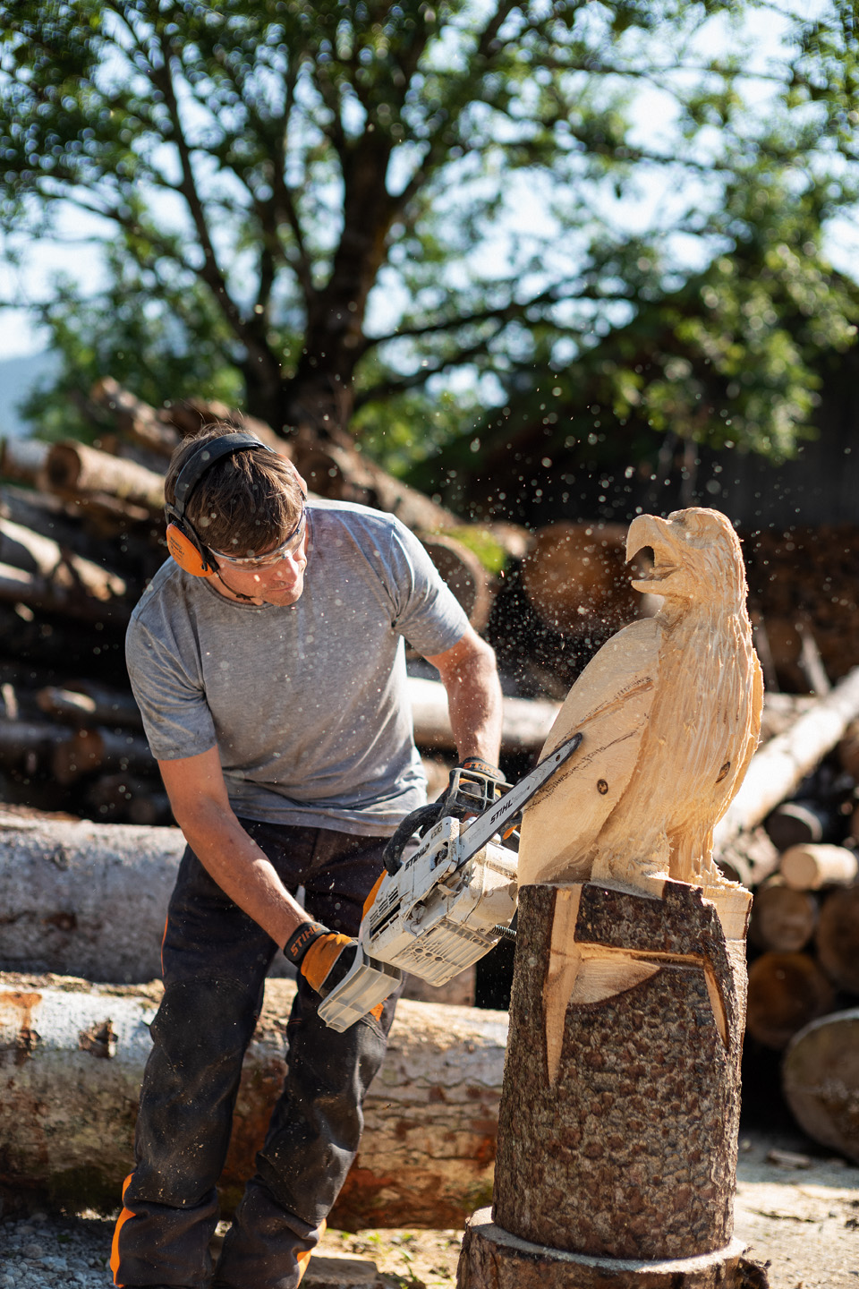 Un hombre creando una escultura de águila con una motosierra de gasolina STIHL MSE 193 CE con espada de talla.