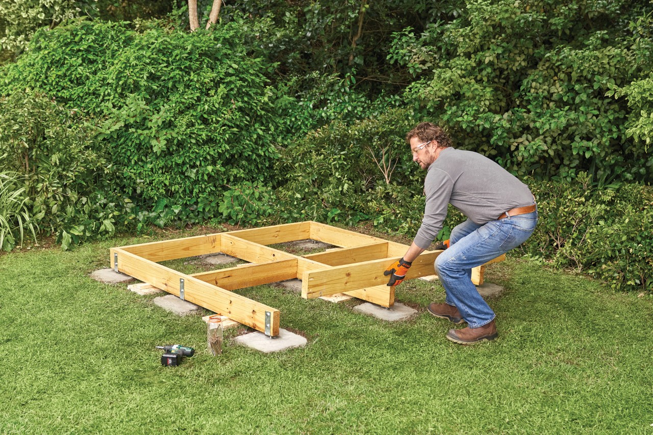 Cómo hacer una caseta de madera para el jardín: un hombre construyendo el marco base de madera de una caseta. 