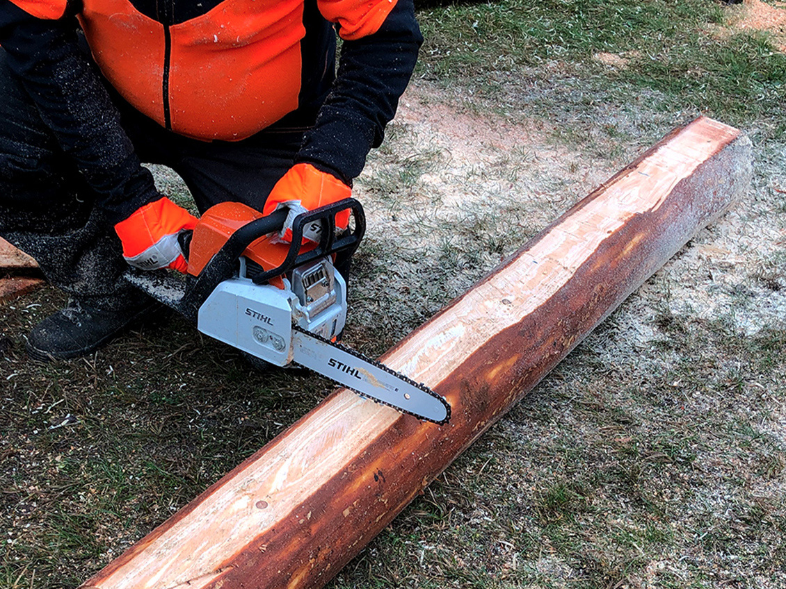 Crea tu propia mesa de jardín: una persona con ropa de protección usando una motosierra de gasolina STIHL MS 170.