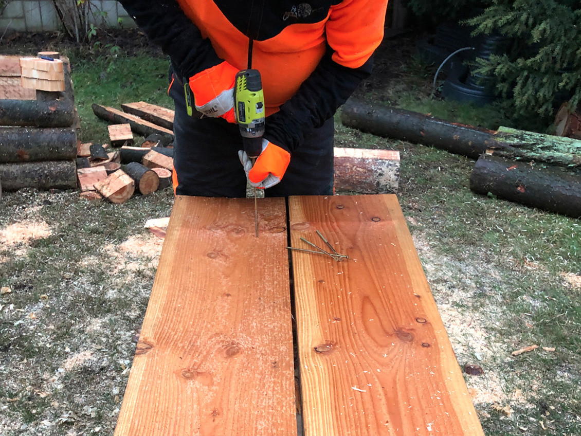 Construir mesa de madera para jardín: proceso de fijado del tablero a las patas.