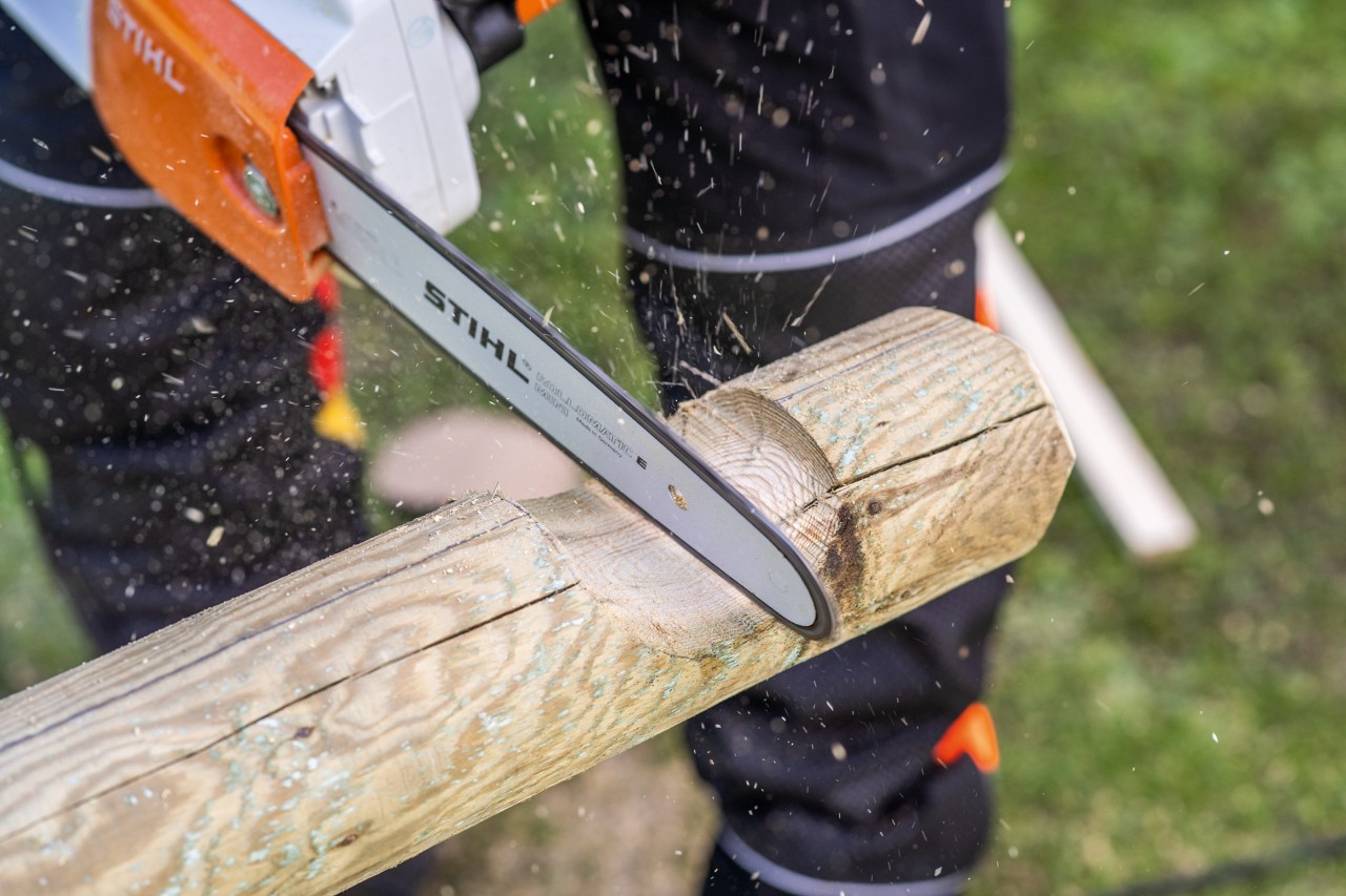 Corte de una muesca curvada para construir un arenero con un tronco y una motosierra STIHL en marcha.