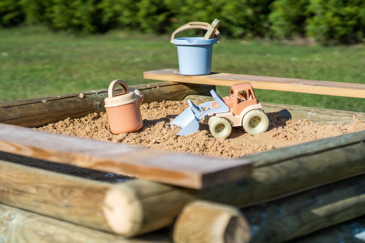 Cubos, rastrillos y palas en un cajón de arena, realizado por alguien que sabe cómo construir un arenero para niños.