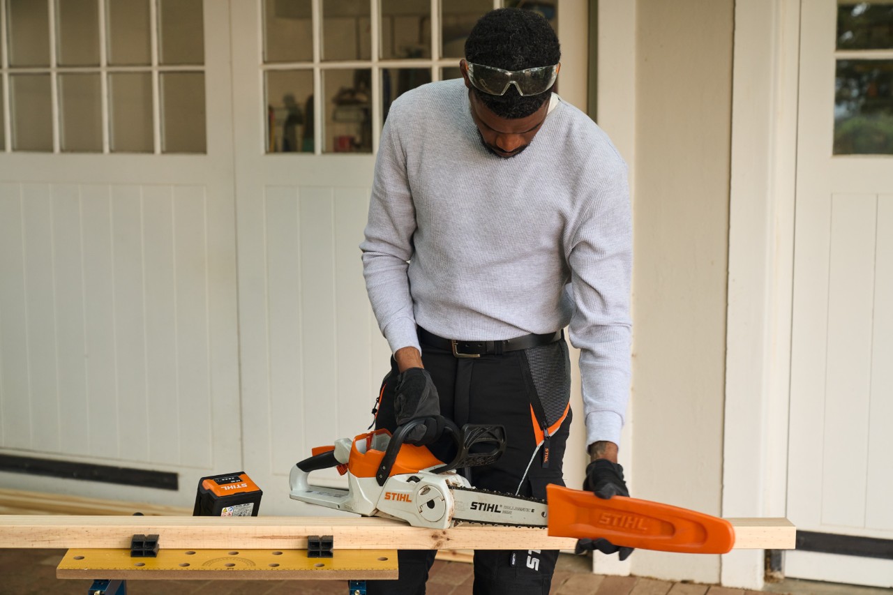 Un hombre delante de una mesa de taller retira el protector de una motosierra de batería STIHL MSA 70 