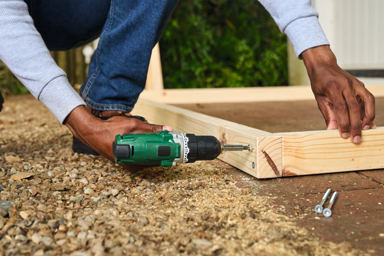 Un hombre taladra orificios con el destornillador a batería para la portería de fútbol
