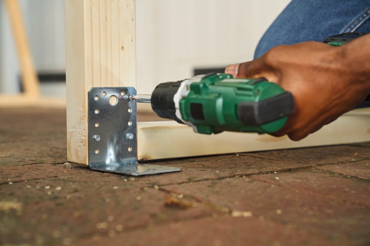 Una persona atornilla los soportes de anclaje al suelo para una portería de fútbol