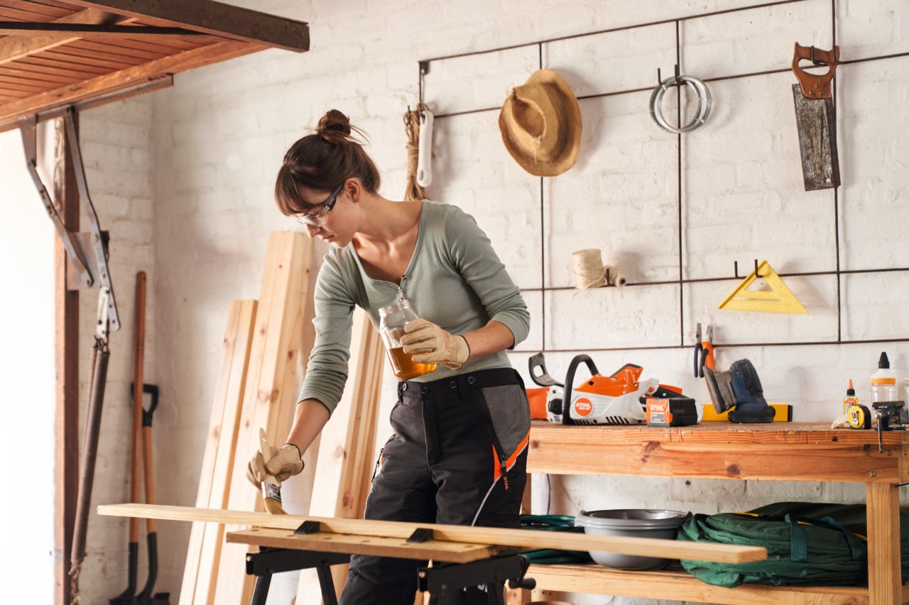 Una mujer engrasa un listón de madera en un taller