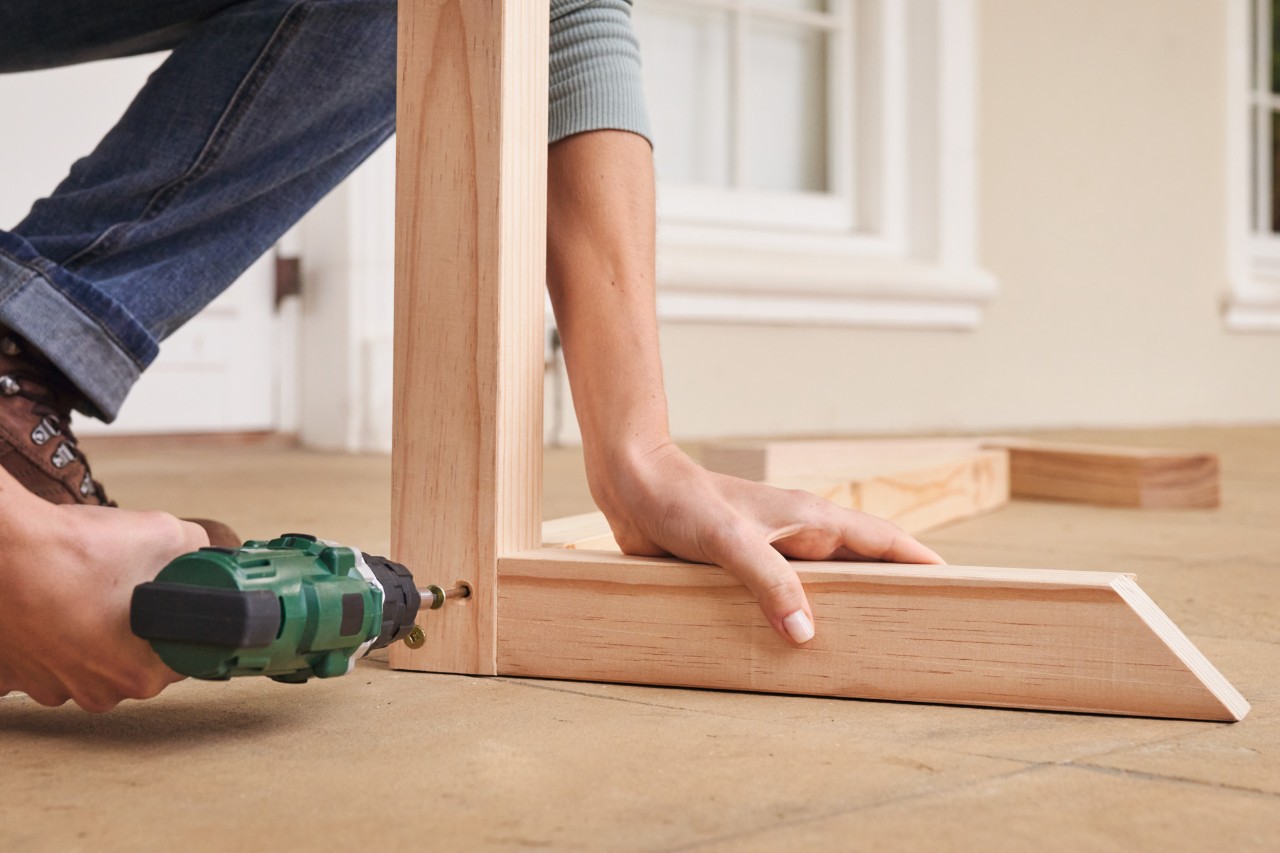 Una persona atornilla dos piezas de madera formando un ángulo