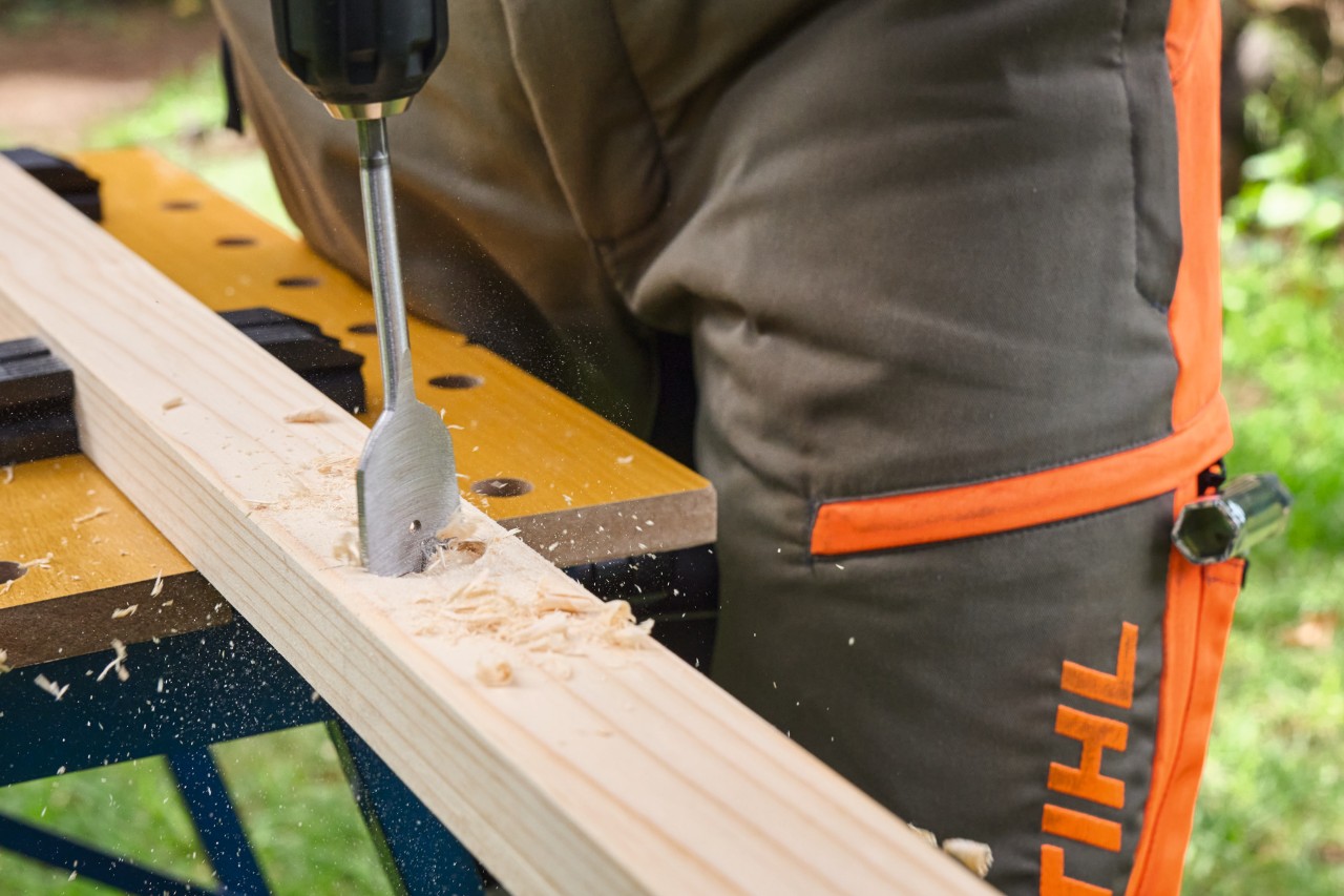 Primer plano de una persona taladrando agujeros ciegos en una tabla de madera