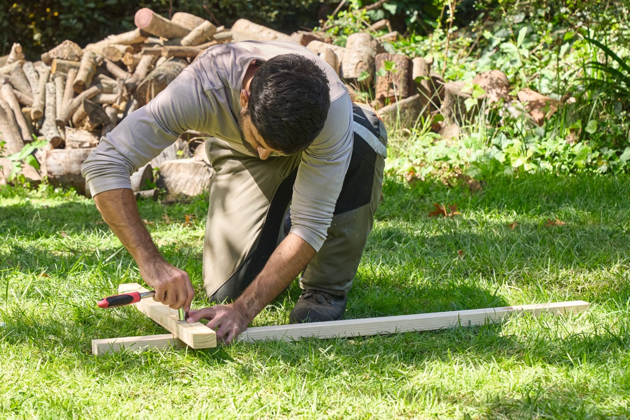 Un hombre utiliza una carraca para apretar dos piezas de madera dispuestas en ángulo recto
