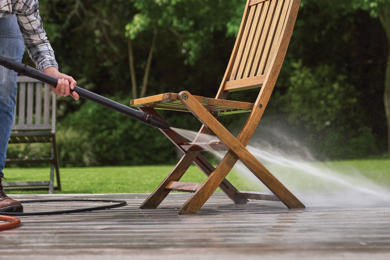 Cómo limpiar muebles de jardín: una hidrolimpiadora STIHL RE 130 Plus limpiando una silla de jardín en un patio.