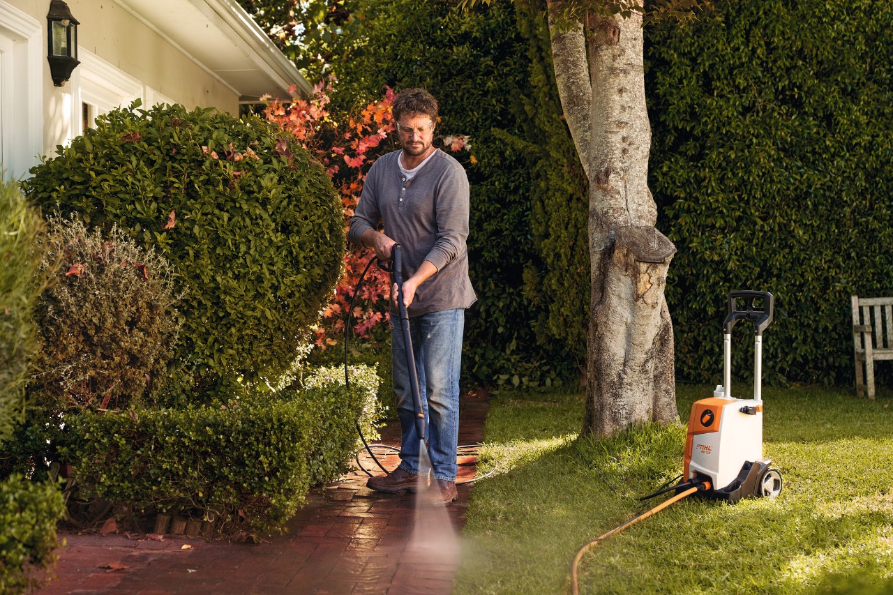 Un hombre limpia los adoquines delante de su casa con la hidrolimpiadora STIHL RE 110