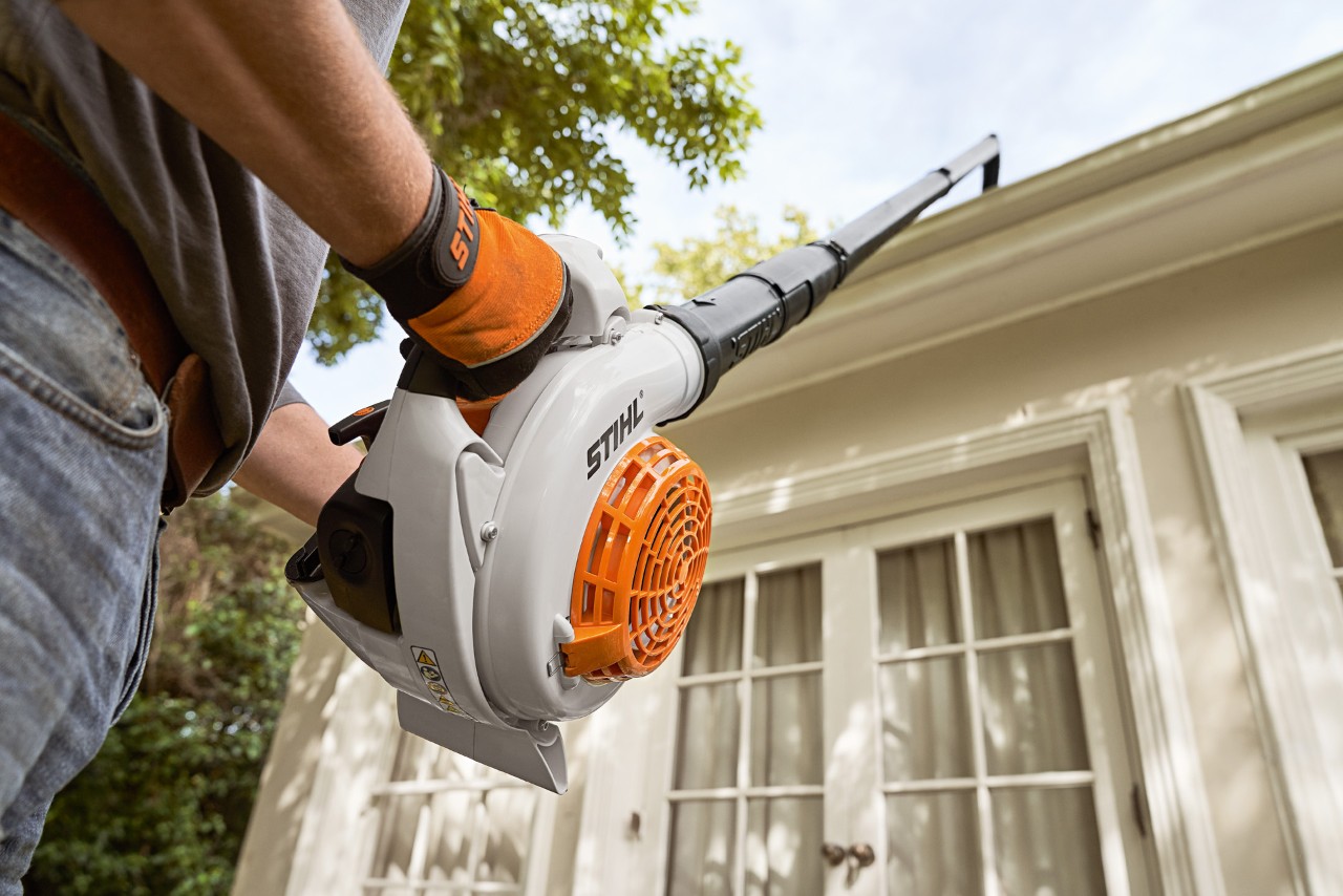 Foto de un juego de limpieza de canalones STIHL y un soplador usado a cargo de la limpieza de canalones de una casa.