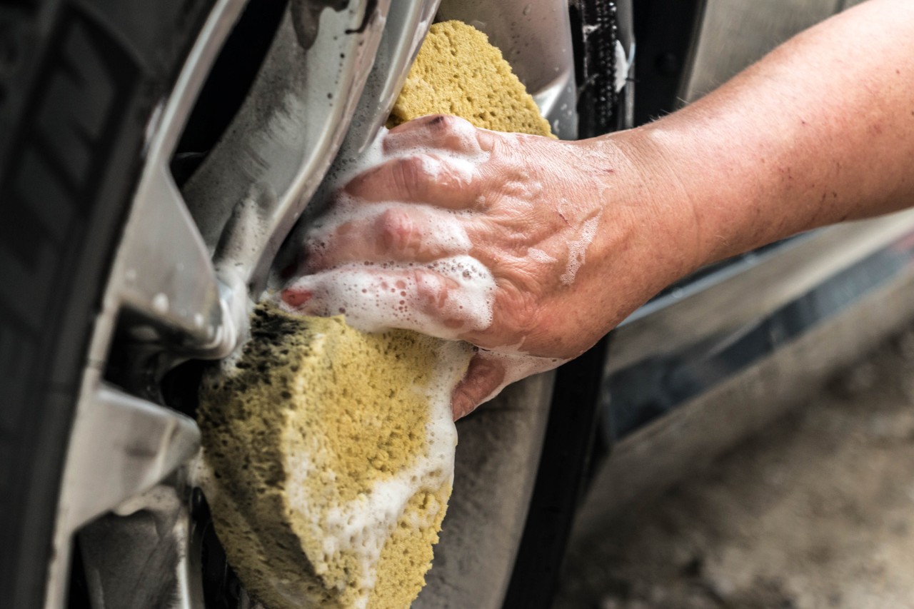 Primer plano de la limpieza de las llantas con una esponja después del lavado a presión de coche.