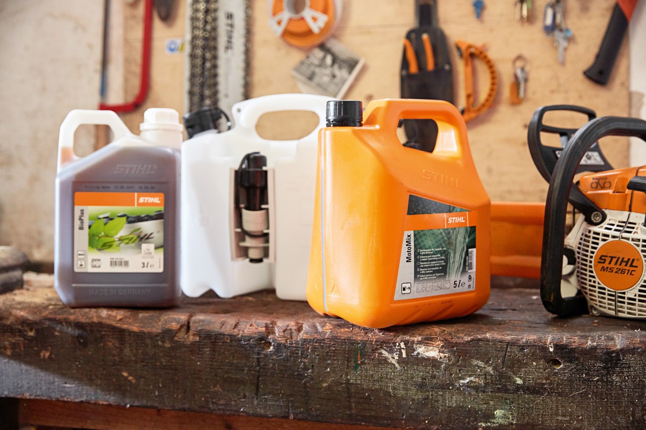 Bidón de mezcla para STIHL MotoMix, aceite y gasolina y una motosierra de gasolina STIHL MS 261 C en un taller