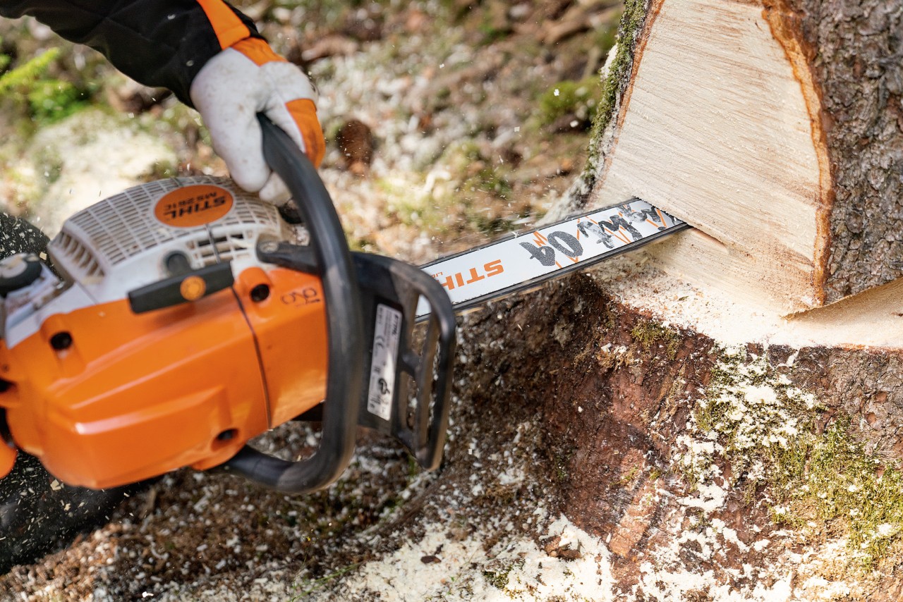 Una persona con motosierra de gasolina STIHL MS 261 C-M corta un tronco en el bosque