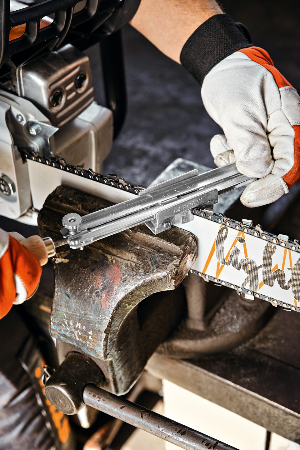 Primer plano de una guía de portalimas STIHL colocada en una espada STIHL Light 04 que está sujeta en una abrazadera